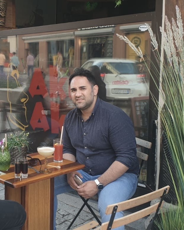 Amin Alamdari i 2021, ved et kafébord med en drink